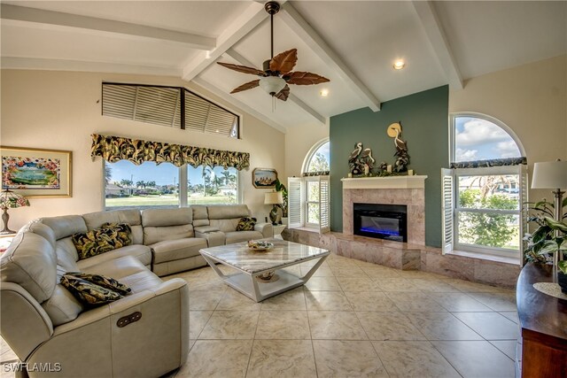 living room featuring a fireplace, ceiling fan, light tile patterned floors, and high vaulted ceiling