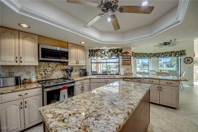 kitchen with a center island, appliances with stainless steel finishes, sink, and a raised ceiling