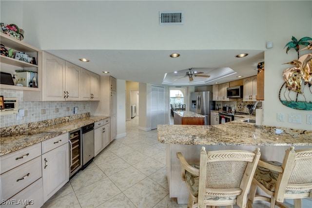 kitchen with kitchen peninsula, appliances with stainless steel finishes, light stone counters, and a kitchen breakfast bar