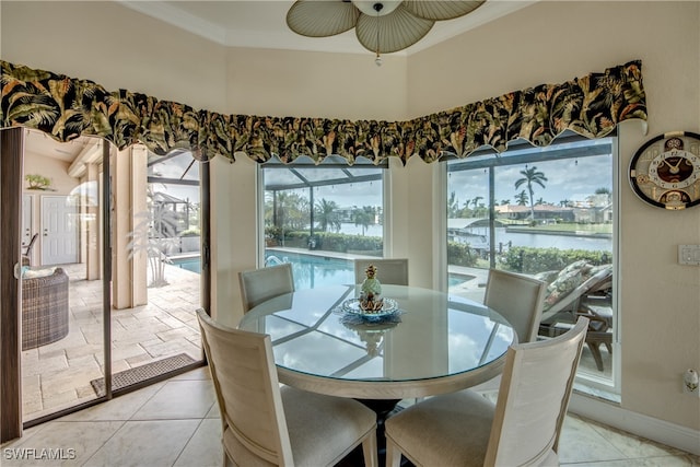 dining space featuring ornamental molding, a water view, ceiling fan, and light tile patterned floors