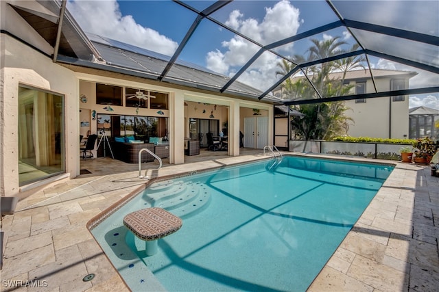 view of pool featuring glass enclosure, outdoor lounge area, a patio, and ceiling fan