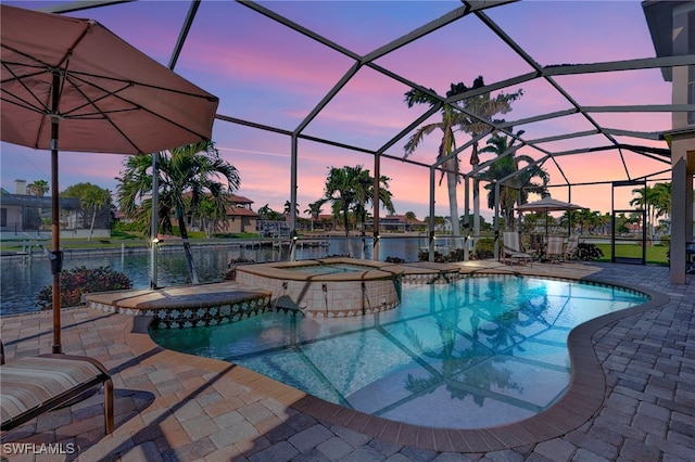 pool at dusk with a lanai, an in ground hot tub, a water view, and a patio