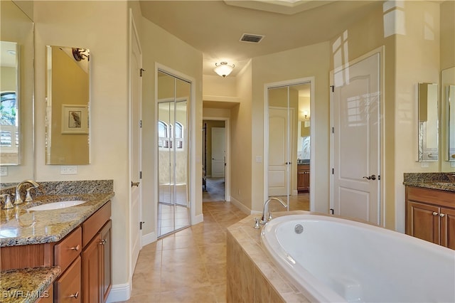 bathroom with vanity, a relaxing tiled tub, tile patterned floors, and plenty of natural light