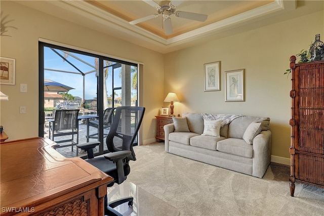 carpeted home office featuring a raised ceiling, ceiling fan, and ornamental molding