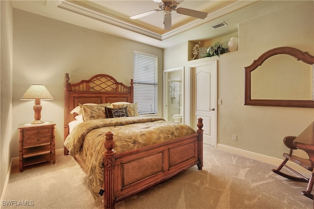 bedroom with light colored carpet, ensuite bath, ceiling fan, and a tray ceiling