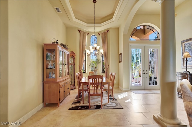 tiled dining area featuring french doors, a towering ceiling, an inviting chandelier, and ornate columns