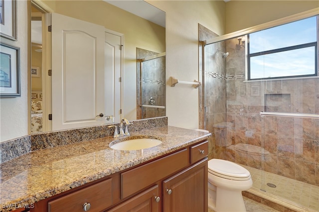 bathroom featuring a shower with door, vanity, and toilet