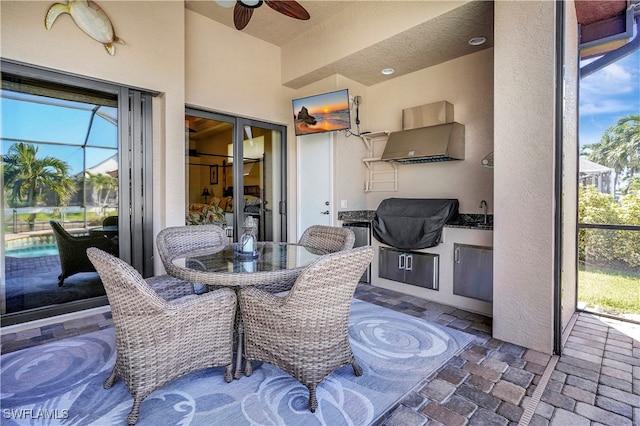 view of patio featuring grilling area, glass enclosure, ceiling fan, and sink