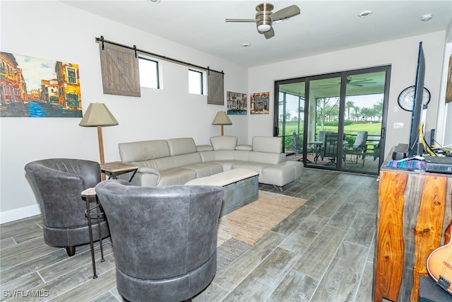 living room featuring hardwood / wood-style flooring, a barn door, and ceiling fan