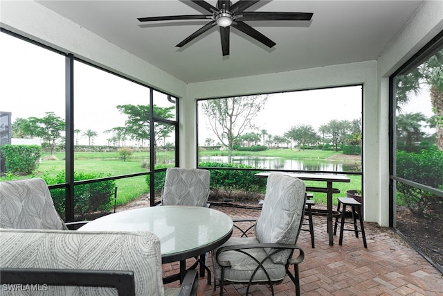 sunroom featuring a water view and ceiling fan