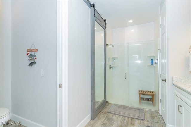 bathroom with hardwood / wood-style floors, vanity, toilet, and a shower with door
