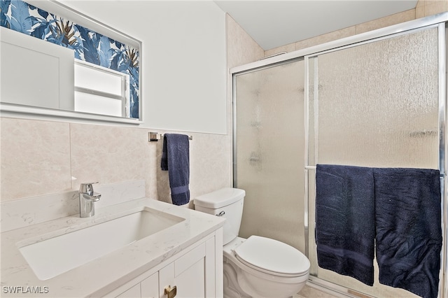 bathroom featuring vanity, a shower with shower door, tile walls, and toilet