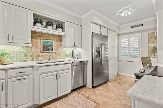 kitchen with light stone counters, ornamental molding, stainless steel appliances, and white cabinets