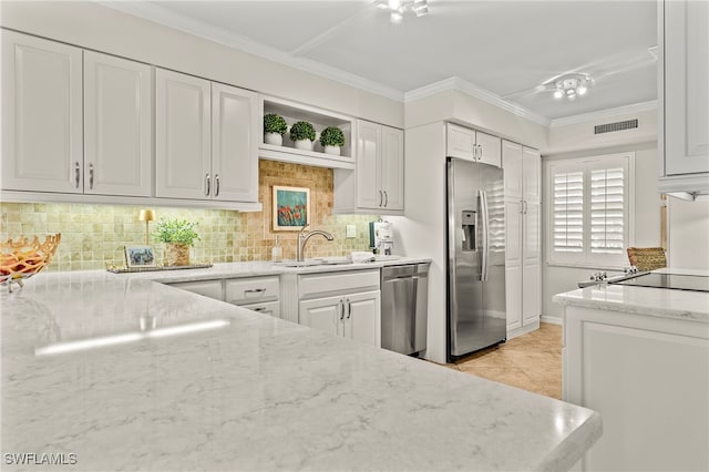 kitchen with appliances with stainless steel finishes, sink, white cabinets, ornamental molding, and light stone countertops