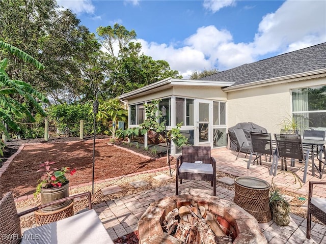 rear view of property with a patio, a sunroom, and an outdoor fire pit