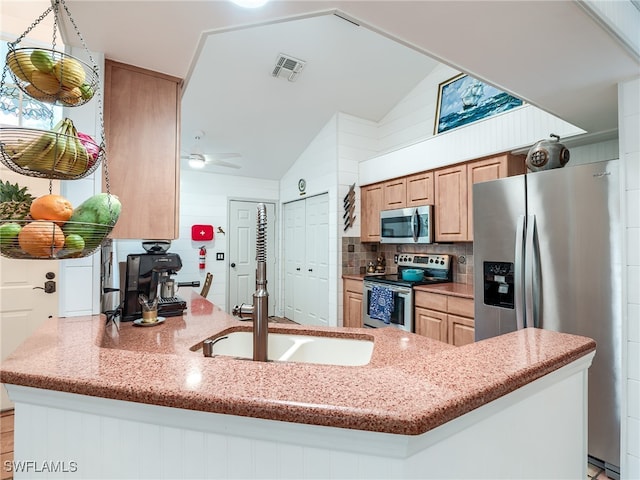 kitchen featuring tasteful backsplash, appliances with stainless steel finishes, kitchen peninsula, lofted ceiling, and ceiling fan