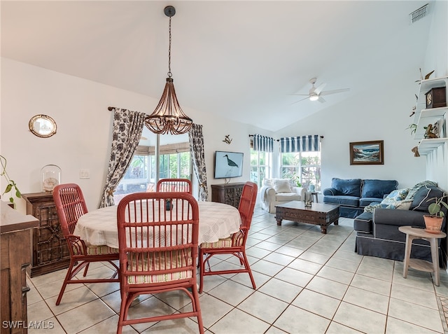 dining area featuring ceiling fan with notable chandelier, light tile patterned floors, and vaulted ceiling