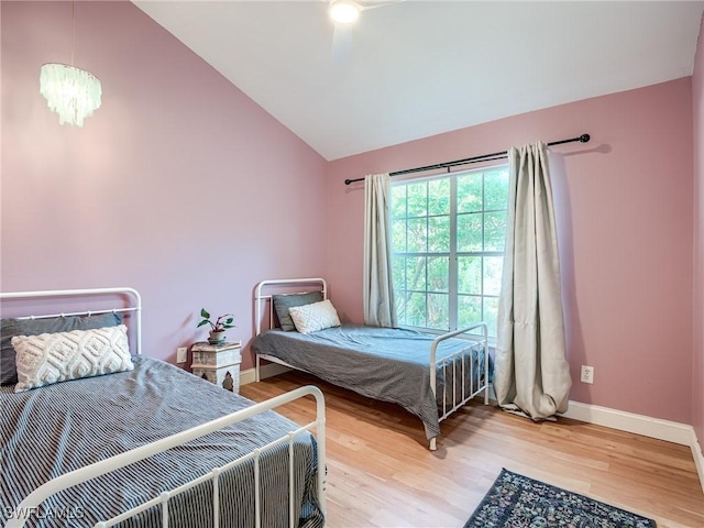 bedroom with ceiling fan with notable chandelier, vaulted ceiling, and wood-type flooring