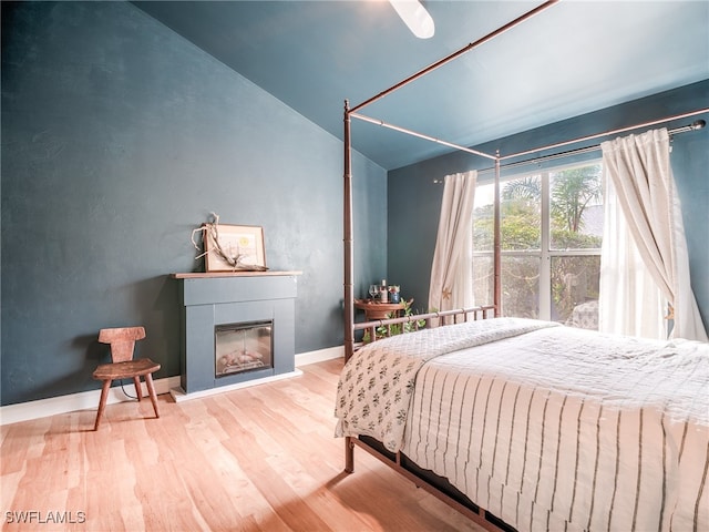 bedroom featuring ceiling fan, light hardwood / wood-style flooring, and lofted ceiling