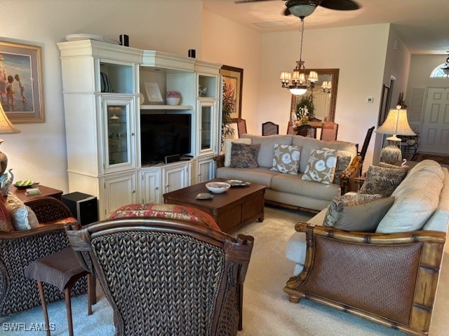 carpeted living room with ceiling fan with notable chandelier