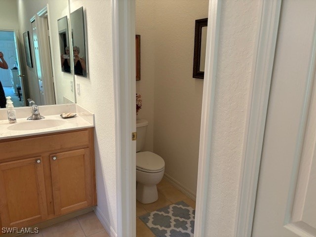 bathroom with toilet, vanity, and tile patterned floors