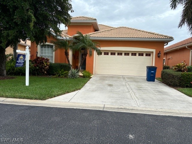 mediterranean / spanish home featuring a garage and a front yard