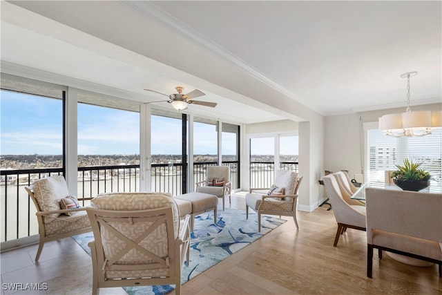 sunroom / solarium featuring a water view, a healthy amount of sunlight, and ceiling fan with notable chandelier