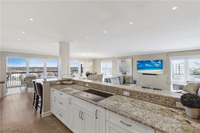 kitchen featuring black electric stovetop, pendant lighting, a kitchen breakfast bar, dark hardwood / wood-style floors, and white cabinetry