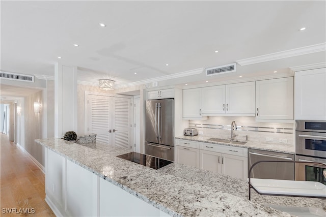 kitchen featuring white cabinetry, sink, light stone counters, appliances with stainless steel finishes, and light wood-type flooring