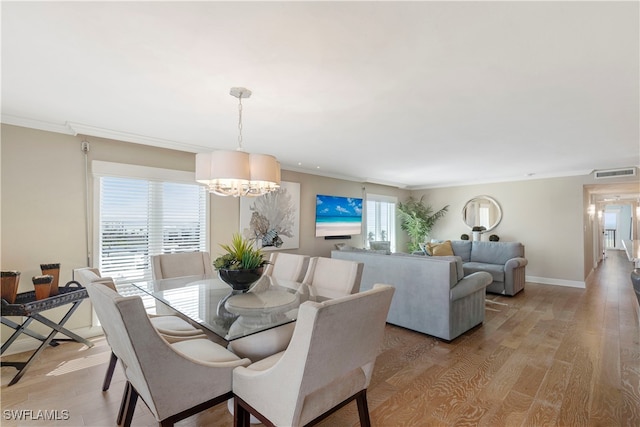 dining room with light hardwood / wood-style flooring, a chandelier, crown molding, and plenty of natural light