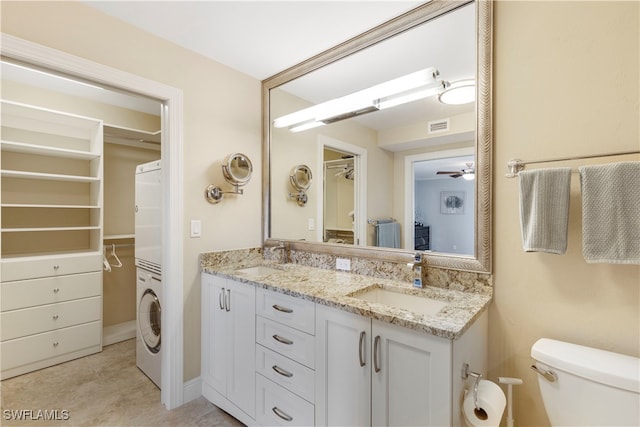 bathroom with toilet, stacked washing maching and dryer, vanity, and ceiling fan