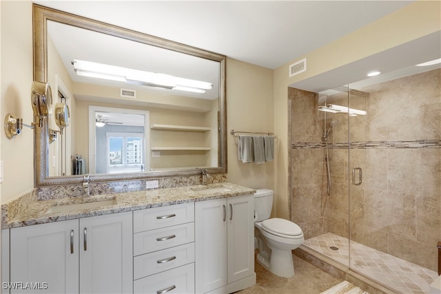 bathroom featuring toilet, vanity, ceiling fan, and a shower with shower door