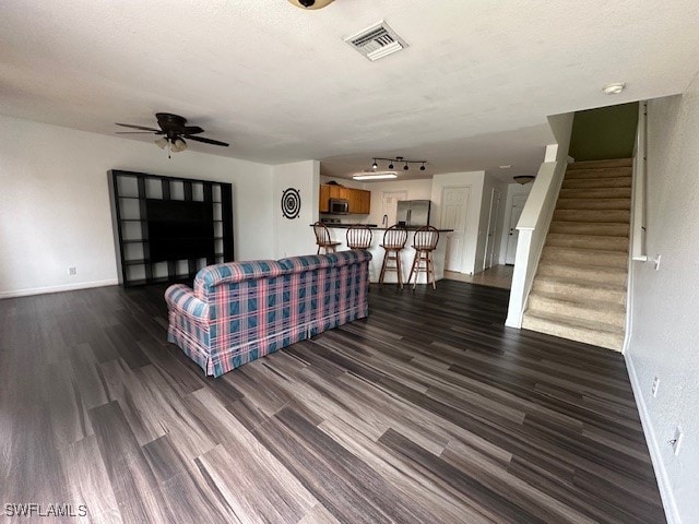 living room featuring ceiling fan, dark wood-type flooring, and a textured ceiling