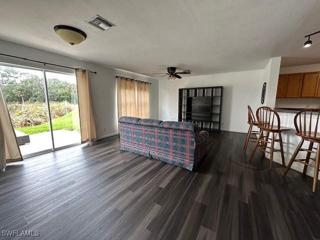 living room with a textured ceiling, dark hardwood / wood-style floors, and ceiling fan