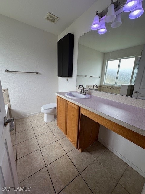 bathroom with toilet, vanity, and tile patterned floors