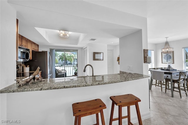 kitchen featuring stainless steel appliances, light stone counters, and kitchen peninsula