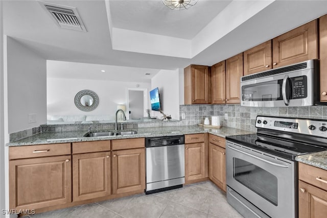 kitchen featuring appliances with stainless steel finishes, light stone countertops, sink, and light tile patterned floors