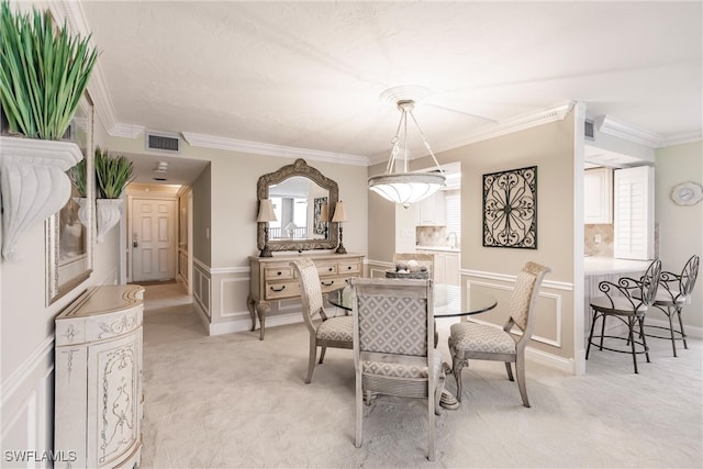 carpeted dining room with sink and crown molding