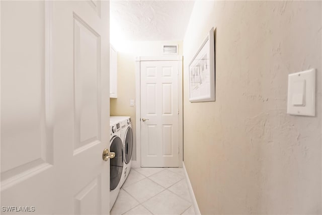 washroom with cabinets, light tile patterned flooring, a textured ceiling, and independent washer and dryer