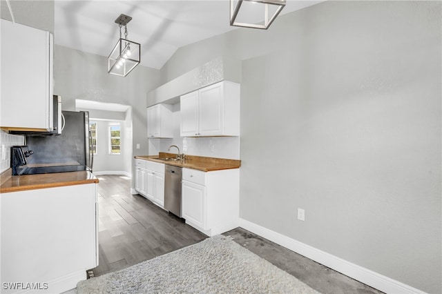 kitchen featuring white cabinetry, lofted ceiling, decorative light fixtures, and stainless steel appliances