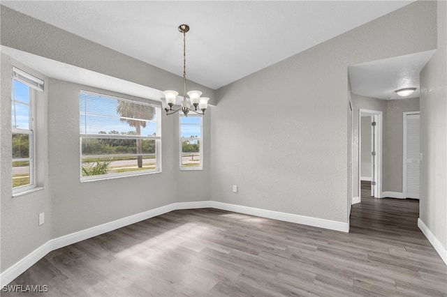 unfurnished room featuring hardwood / wood-style flooring and an inviting chandelier