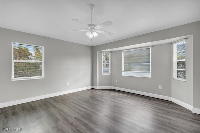 spare room featuring dark hardwood / wood-style flooring, ceiling fan, and a healthy amount of sunlight