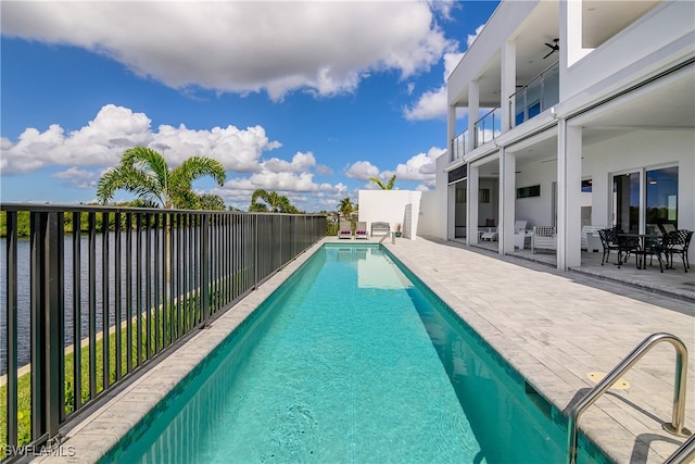 view of swimming pool with ceiling fan, a water view, and a patio