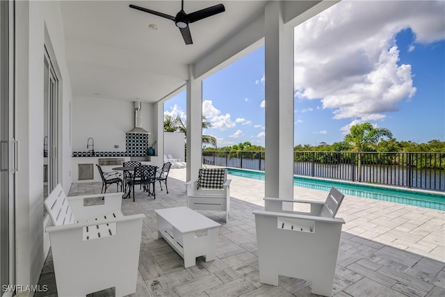 view of patio featuring ceiling fan, a water view, and a fenced in pool