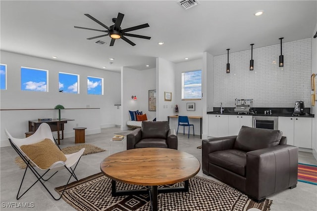 living room featuring wine cooler, ceiling fan, and brick wall