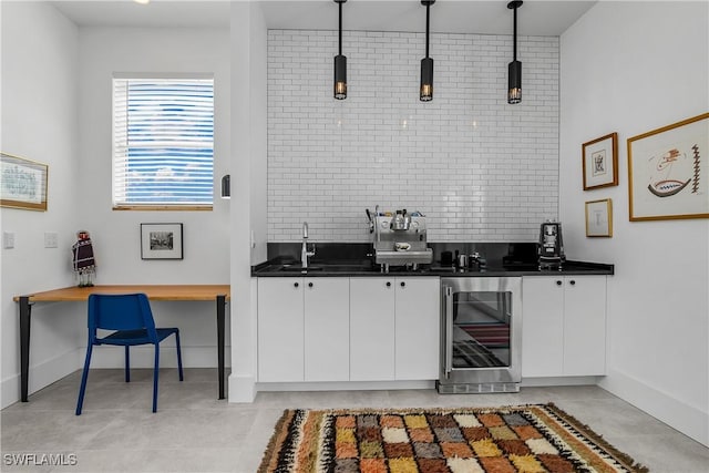 kitchen featuring backsplash, white cabinets, sink, decorative light fixtures, and beverage cooler