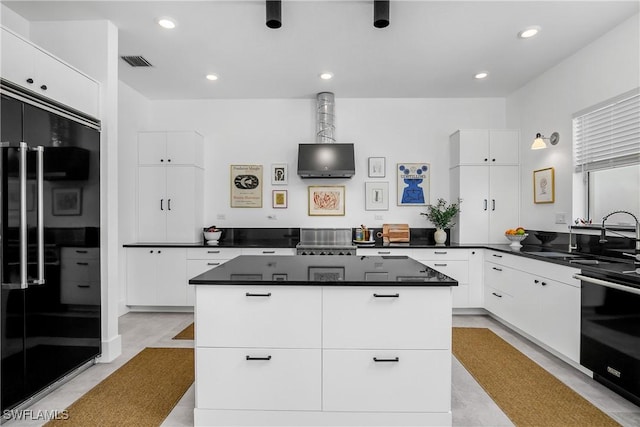 kitchen featuring black fridge, dishwashing machine, a kitchen island, sink, and white cabinetry