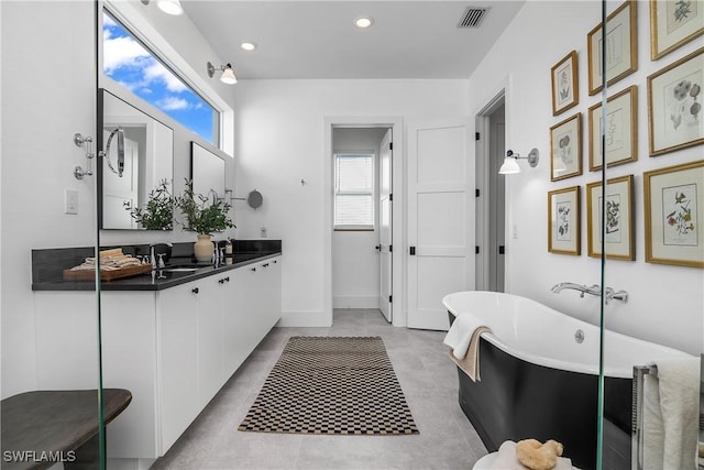 bathroom featuring tile patterned flooring, a bath, and vanity