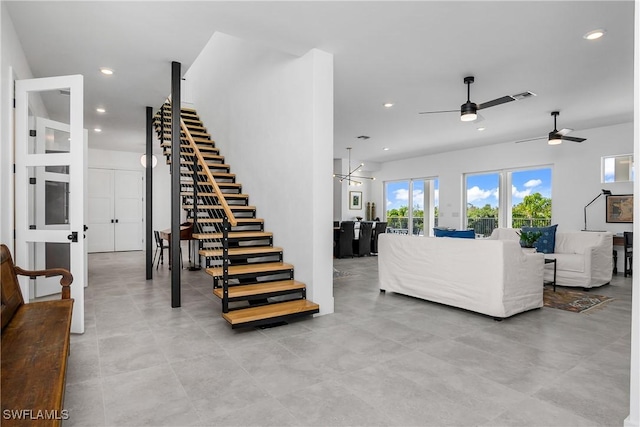 living room featuring ceiling fan with notable chandelier