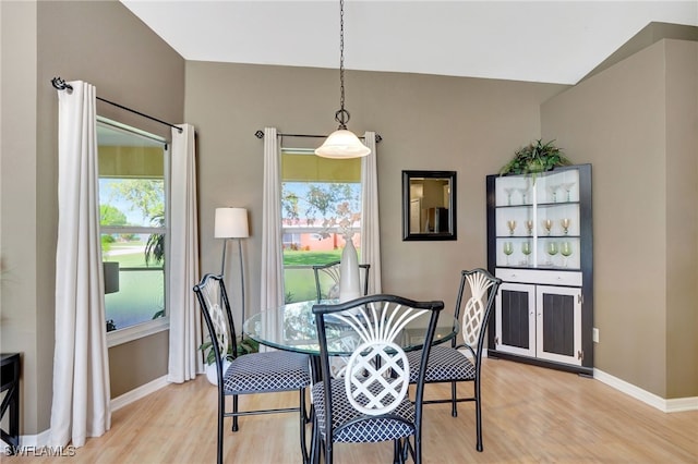 dining area with vaulted ceiling and light wood-type flooring